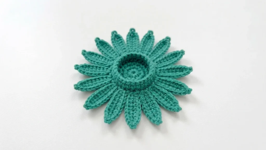 Green crocheted flower base with a round hollow center and pointed sepals radiating around it on a white background.