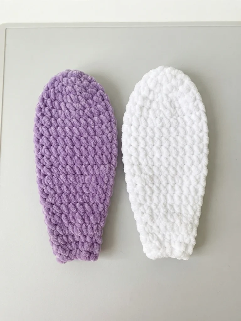 Two flat crochet ear panels, one lilac and one white, lying side by side on a light surface