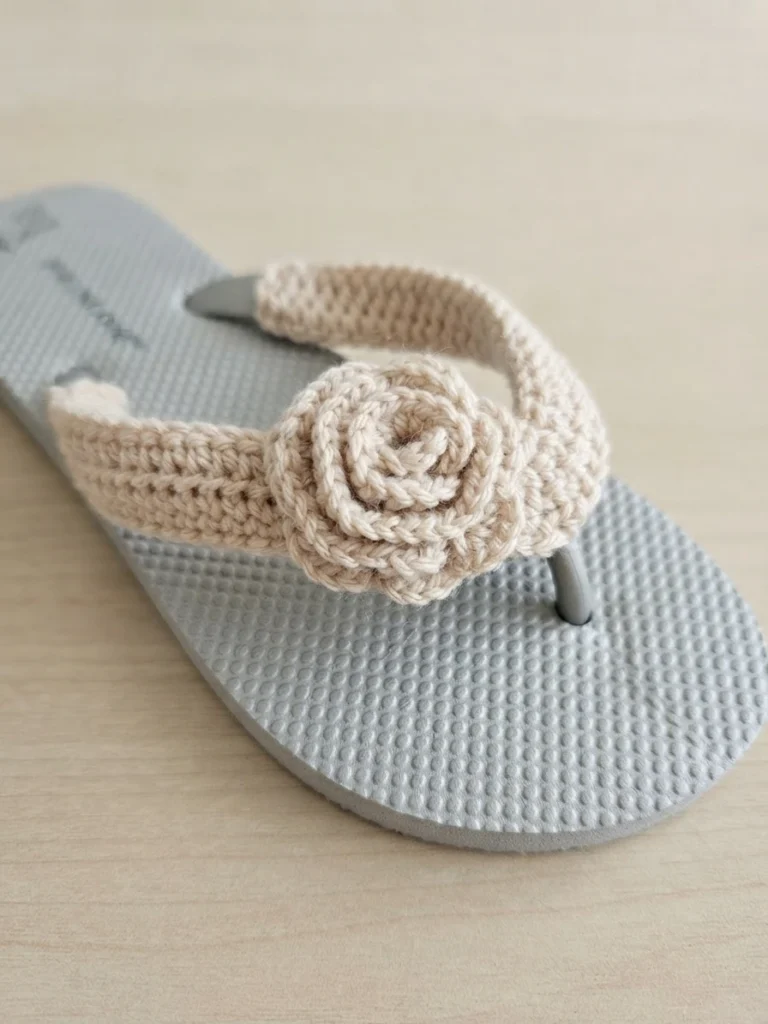 Finished flip flop slipper with a cream crochet strap cover and a crochet rose in the center