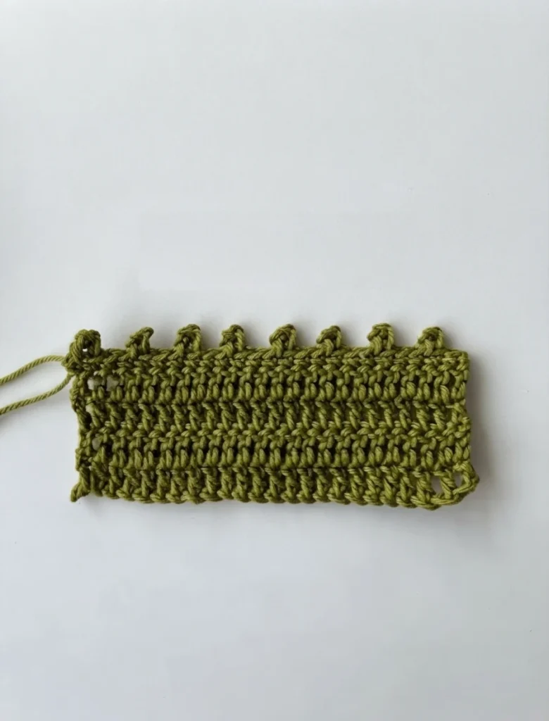 Olive green crochet swatch with small picot loops along the top edge on a plain white background