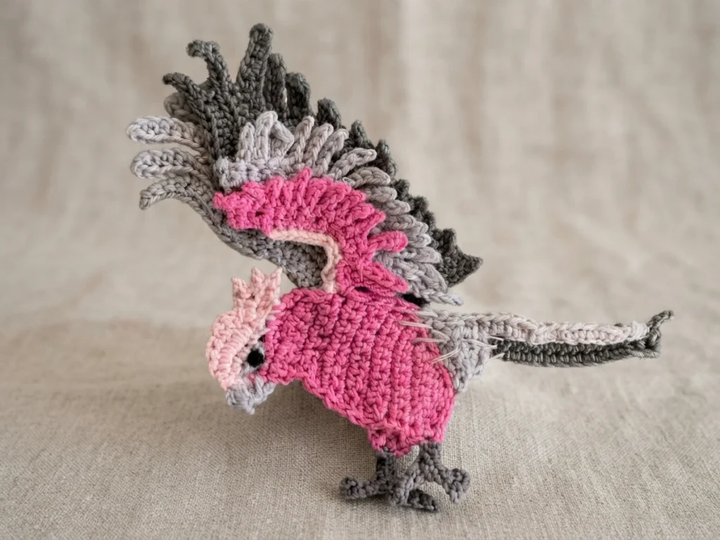 Crocheted pink and grey galah parrot with raised crest