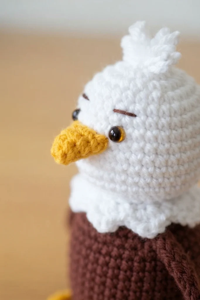 Close-up of a crocheted bald eagle with a white head, yellow beak and brown body
