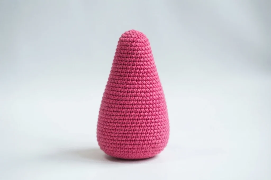 Single pink crocheted tapered piece standing upright on a white background