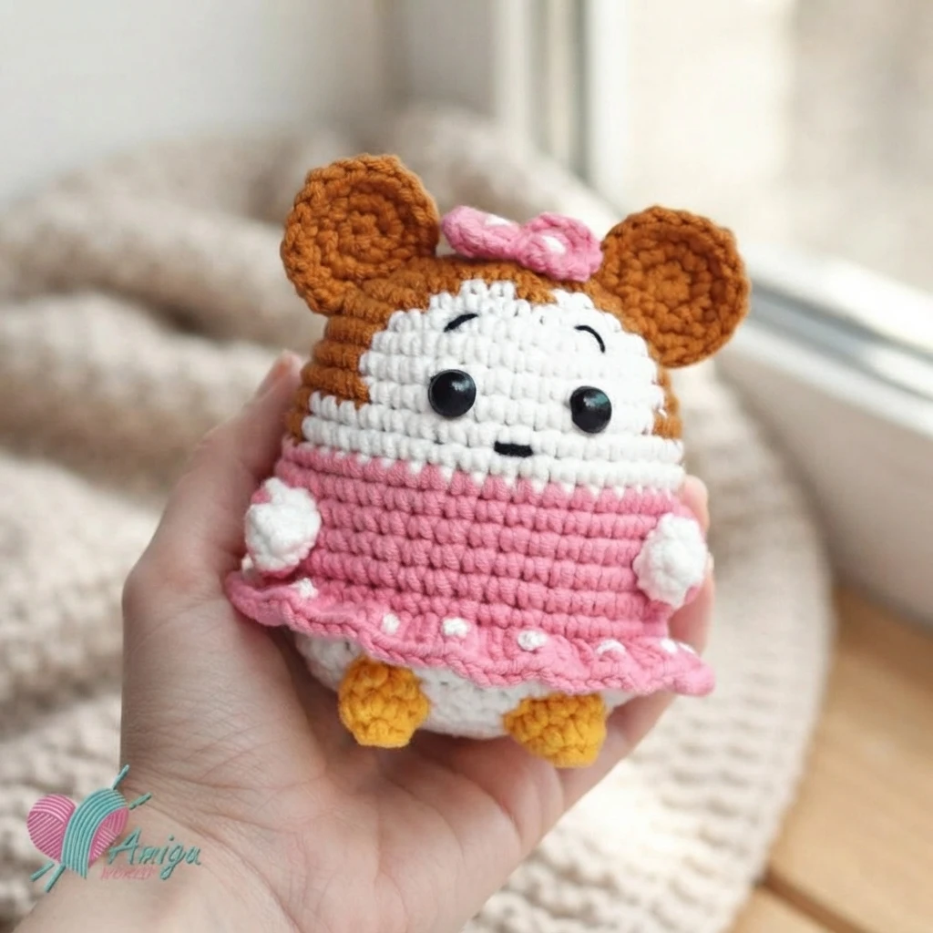 Hand holding a chibi Minnie Mouse amigurumi with brown ears, a pink bow, a pink dress and yellow feet