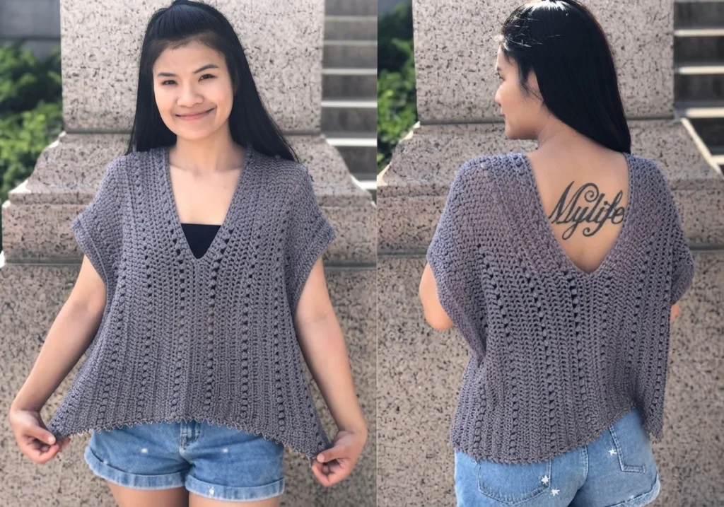 A woman models a grey crocheted V-neck summer top from the front and back, worn over a black top with denim shorts, standing by a stone pillar.